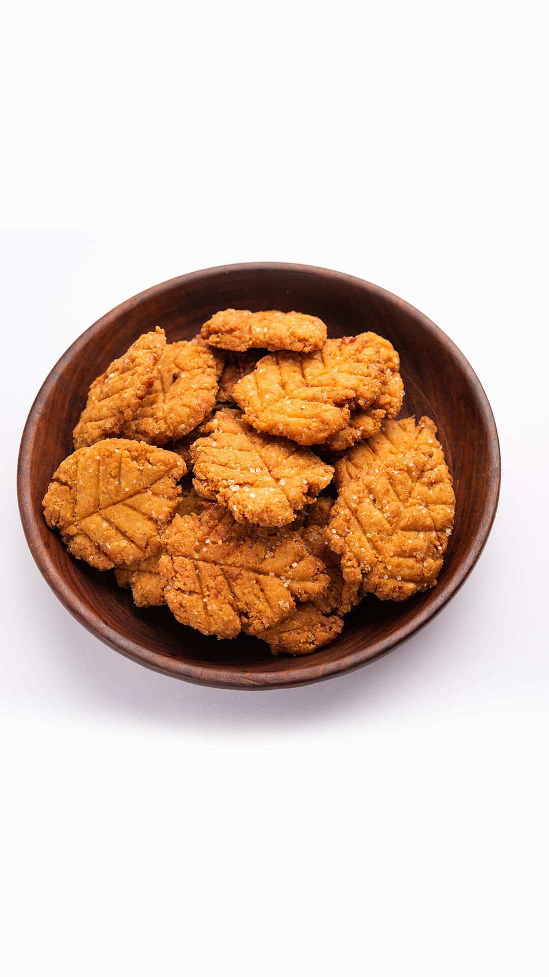 A wooden bowl of Thekua, the essential traditional sweet prasad for the Chhath Puja festival rituals.